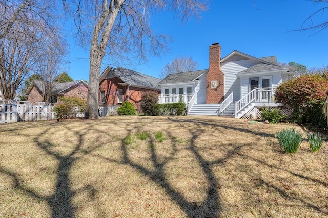 back of house with a lawn, a chimney, and fence