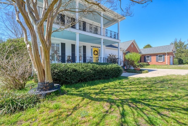view of front of house featuring a front lawn and a balcony