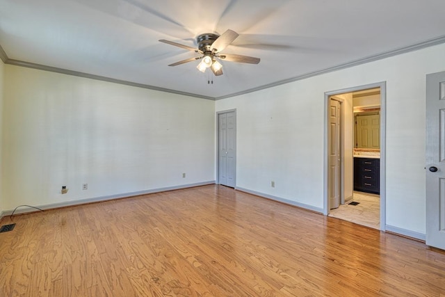 unfurnished bedroom featuring crown molding, light wood-style flooring, baseboards, and ensuite bathroom
