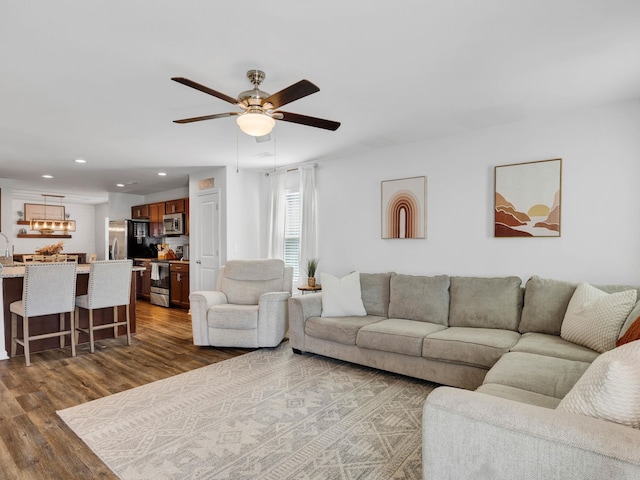 living area featuring recessed lighting, ceiling fan with notable chandelier, and dark wood-style flooring