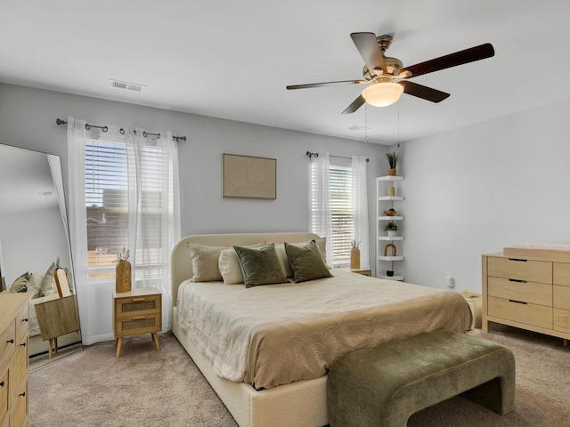 bedroom with a ceiling fan, visible vents, and light carpet