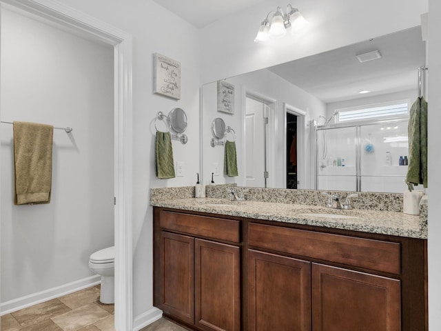 full bathroom with double vanity, toilet, a stall shower, and a sink