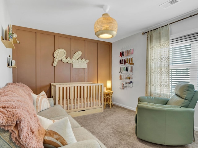 bedroom with visible vents, a nursery area, baseboards, and carpet
