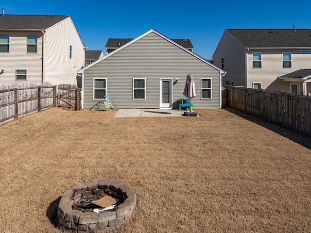 back of property featuring a yard, an outdoor fire pit, a fenced backyard, and a patio area