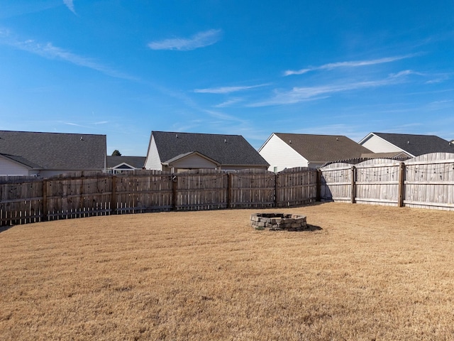 view of yard featuring a residential view, a fenced backyard, and an outdoor fire pit
