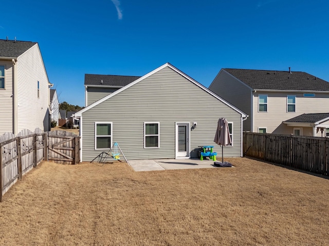 rear view of house featuring a fenced backyard, a lawn, a patio, and a gate