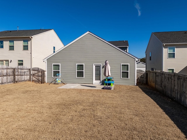 rear view of property featuring a patio, a lawn, a fenced backyard, and a gate