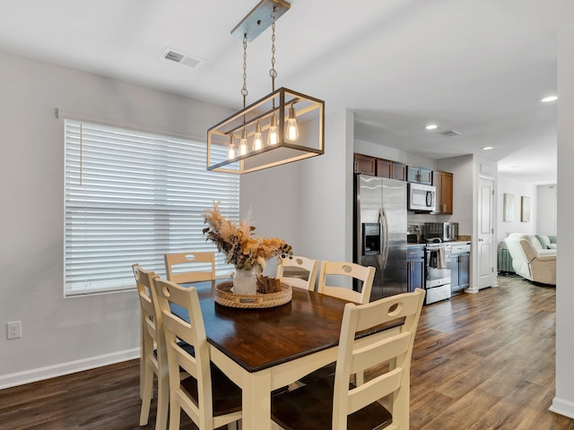 dining room with a chandelier, visible vents, dark wood-type flooring, and baseboards