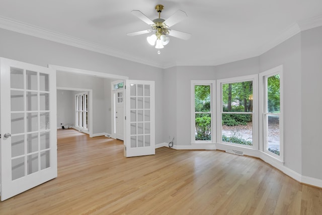 spare room featuring french doors, baseboards, visible vents, light wood-style floors, and ornamental molding