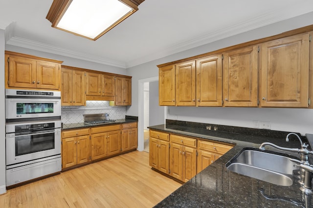 kitchen featuring backsplash, a sink, double oven, a warming drawer, and light wood-style floors