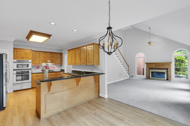 kitchen featuring a peninsula, ceiling fan, stainless steel appliances, open floor plan, and a kitchen breakfast bar