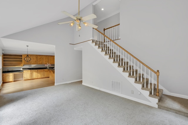 unfurnished living room featuring baseboards, visible vents, stairs, and a ceiling fan