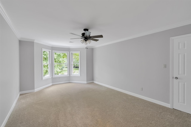 spare room with a ceiling fan, crown molding, baseboards, and light colored carpet
