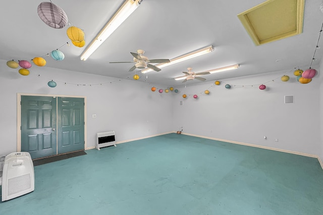 spare room with heating unit, finished concrete flooring, baseboards, and attic access