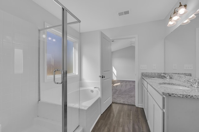 full bath featuring a stall shower, a sink, a garden tub, wood finished floors, and visible vents