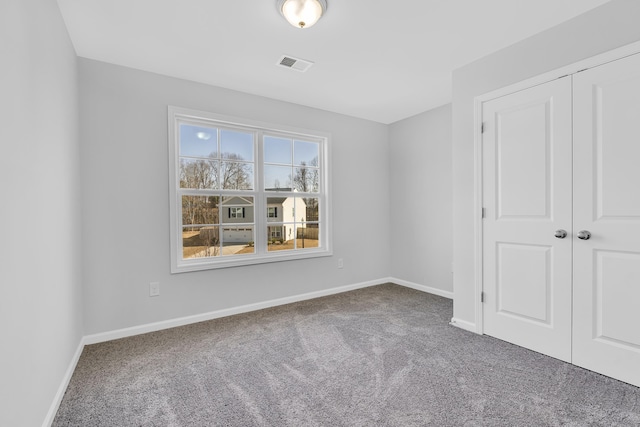 unfurnished bedroom with baseboards, carpet flooring, visible vents, and a closet
