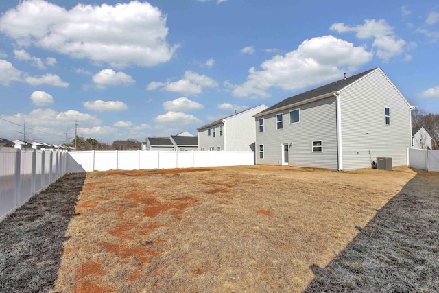 back of property with a fenced backyard, central AC unit, and a lawn