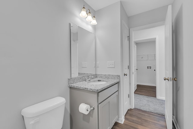 bathroom with baseboards, toilet, wood finished floors, and vanity
