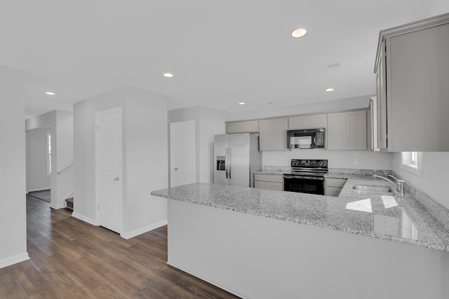 kitchen with a sink, black appliances, a peninsula, and light stone counters