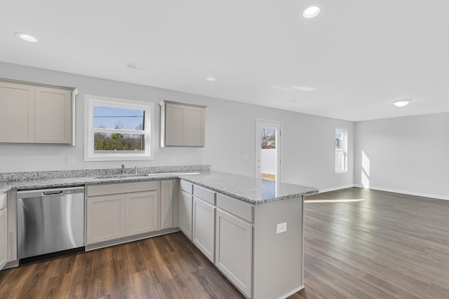 kitchen with stainless steel dishwasher, dark wood-style floors, a sink, and a peninsula