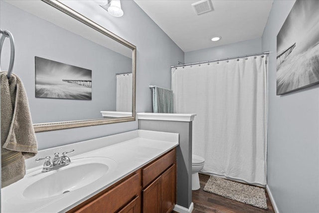 bathroom with a shower with shower curtain, toilet, vanity, wood finished floors, and visible vents