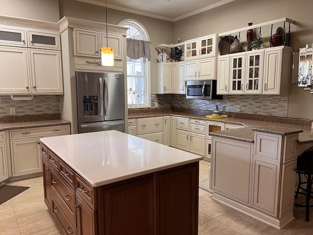 kitchen with a peninsula, crown molding, a kitchen bar, appliances with stainless steel finishes, and glass insert cabinets