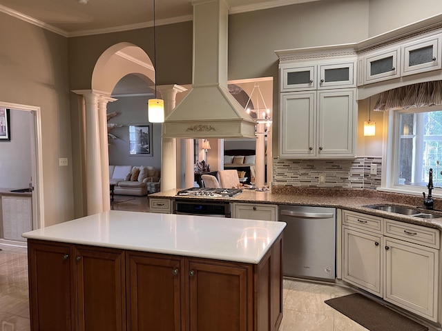kitchen featuring open floor plan, ornate columns, stainless steel appliances, island exhaust hood, and a sink