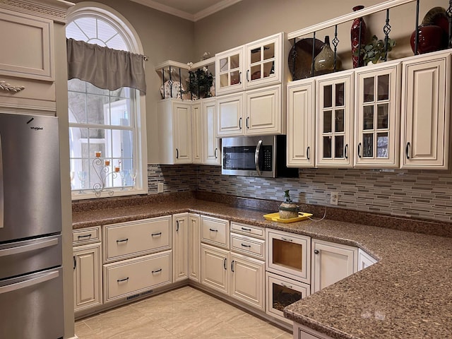 kitchen featuring glass insert cabinets, backsplash, ornamental molding, and appliances with stainless steel finishes