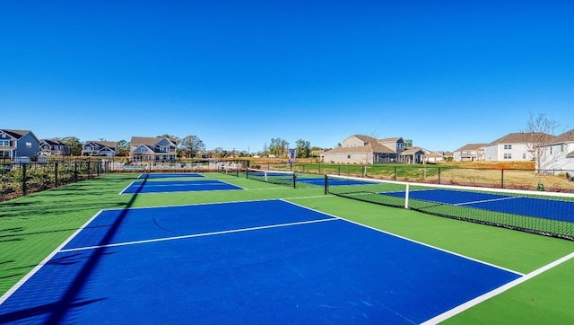 view of tennis court featuring fence and a residential view