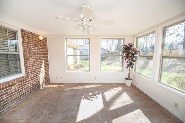 unfurnished sunroom with baseboards and brick wall