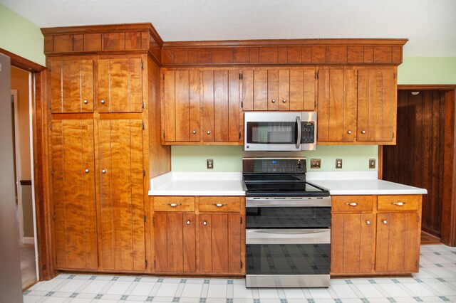 kitchen with brown cabinets, light countertops, light floors, and stainless steel appliances