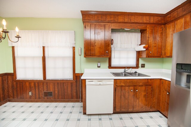 kitchen featuring stainless steel fridge with ice dispenser, a wainscoted wall, a sink, dishwasher, and light floors