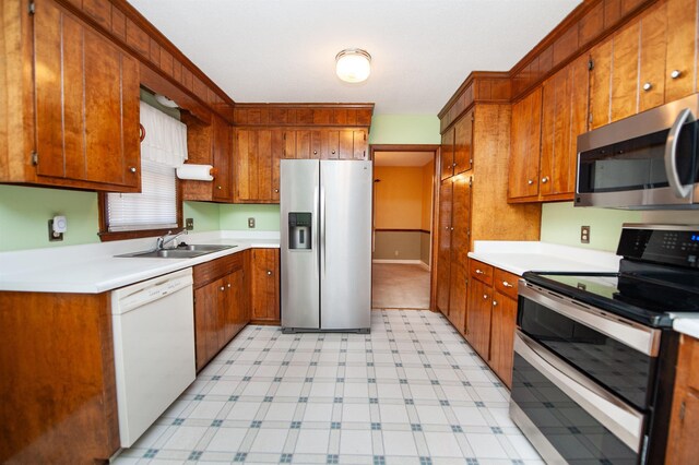 kitchen featuring a sink, stainless steel appliances, brown cabinetry, and light floors