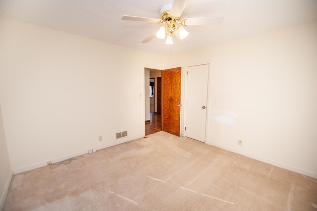 unfurnished room with baseboards, visible vents, a ceiling fan, and light carpet