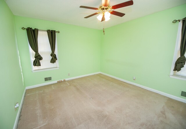 unfurnished room with carpet floors, baseboards, ceiling fan, and visible vents