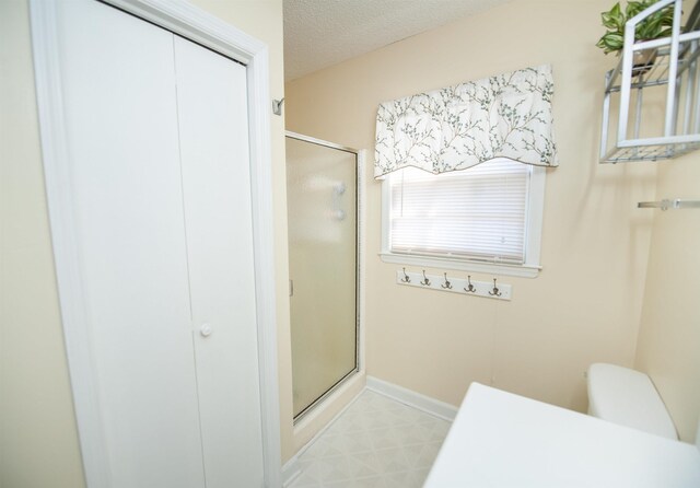 bathroom featuring baseboards, a textured ceiling, a stall shower, and tile patterned flooring