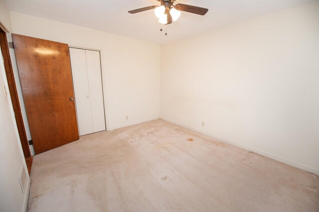 spare room featuring baseboards, ceiling fan, and light carpet