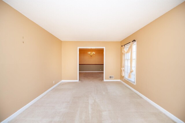 unfurnished room with baseboards, visible vents, an inviting chandelier, and light colored carpet