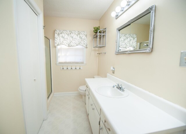bathroom with toilet, vanity, an enclosed shower, and a textured ceiling