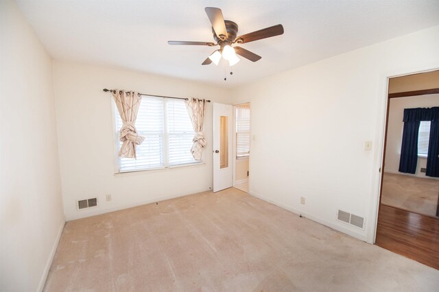 carpeted empty room featuring baseboards, visible vents, and ceiling fan