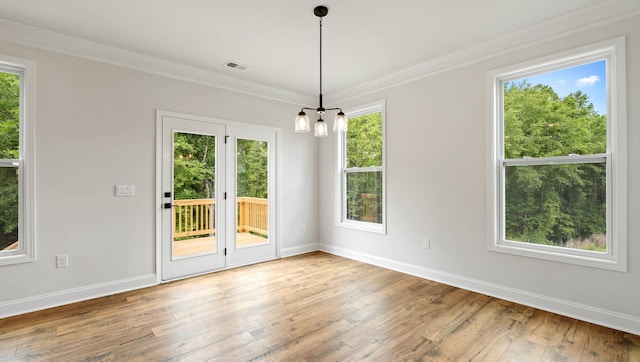 unfurnished dining area with healthy amount of natural light, baseboards, wood-type flooring, and ornamental molding