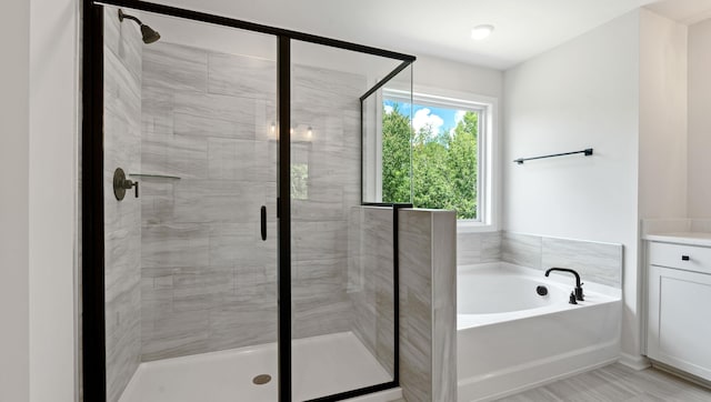 bathroom featuring a stall shower, a bath, and vanity