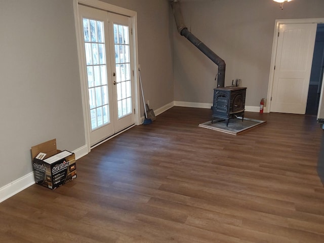 unfurnished living room featuring wood finished floors, baseboards, a wood stove, and a healthy amount of sunlight
