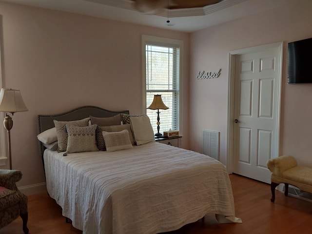 bedroom featuring baseboards, wood finished floors, and visible vents