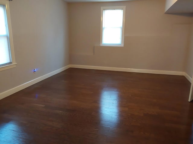spare room with baseboards and dark wood-style flooring