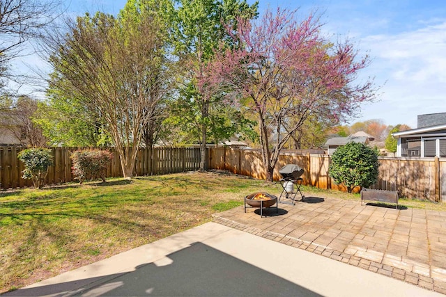 view of yard with a fenced backyard, a fire pit, and a patio area