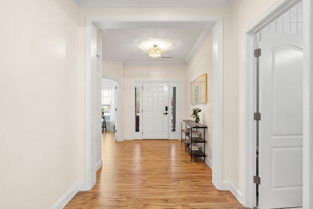 entryway with ornamental molding, baseboards, and light wood-type flooring