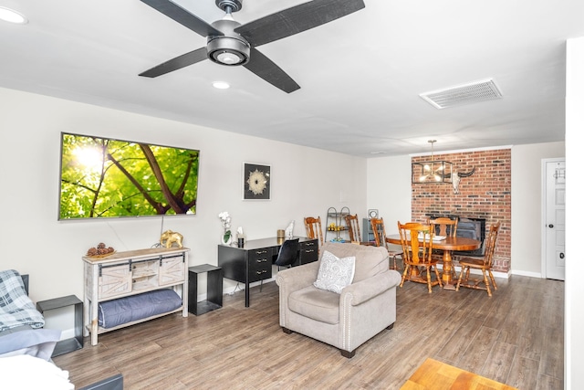 living area featuring light wood finished floors, ceiling fan with notable chandelier, visible vents, and baseboards