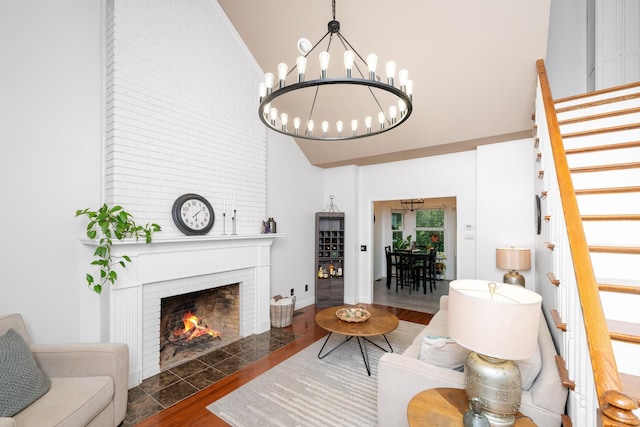 living room with stairs, a notable chandelier, high vaulted ceiling, a fireplace, and wood finished floors
