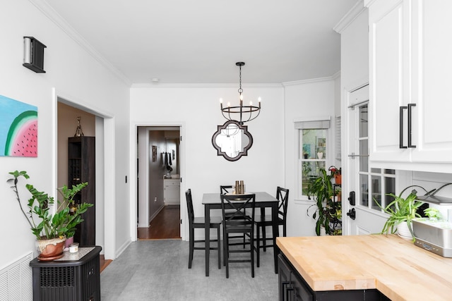 dining room featuring light wood-style flooring, ornamental molding, baseboards, and a chandelier